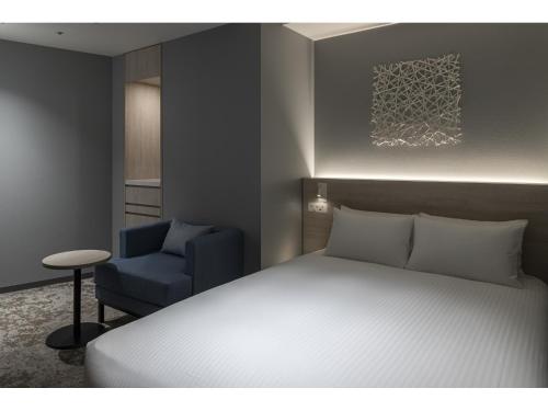 a bedroom with a bed and a blue chair at HOTEL FORZA SAPPORO STATION in Sapporo