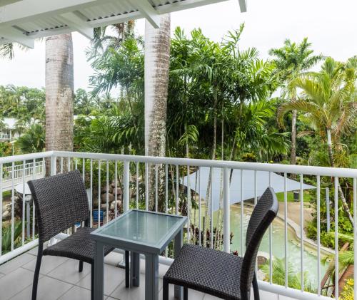 a balcony with chairs and a table and palm trees at Oaks Port Douglas Resort in Port Douglas