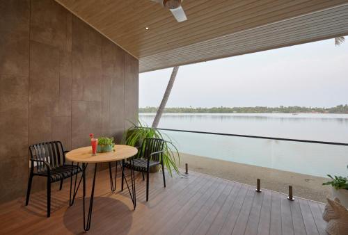 a table and chairs on a deck with a view of the water at Lago Leisure Resort & Spa in Cherai Beach