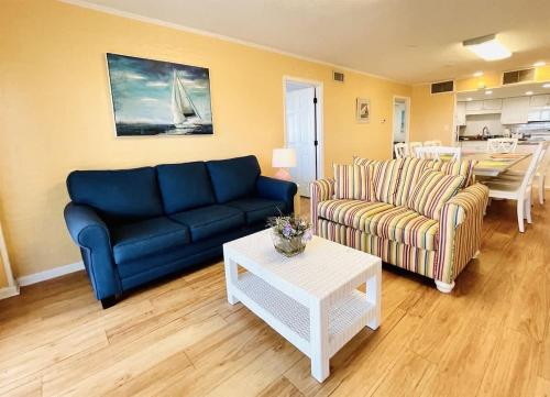 ein Wohnzimmer mit einem blauen Sofa und einem Tisch in der Unterkunft OCEANFRONT HOUSE ON THE SAND 2 Kings 4br 4ba 1st Floor of Triplex SLEEP 12 PGP1 in Myrtle Beach