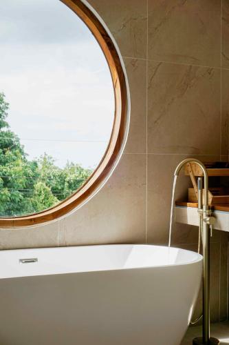 a bath tub in a bathroom with a round window at v32A Blue Horizon Haad Yao, Seaview 3BR Apartment 1st Floor in Ko Phangan