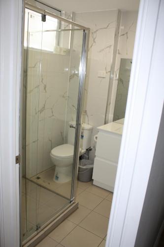 a bathroom with a toilet and a glass shower at Coburg Motor Inn in Melbourne