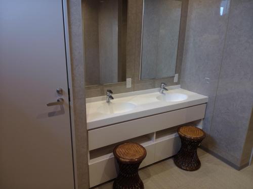 a bathroom with two sinks and a mirror and two stools at Hotel Crown Hills GOI in Ichihara