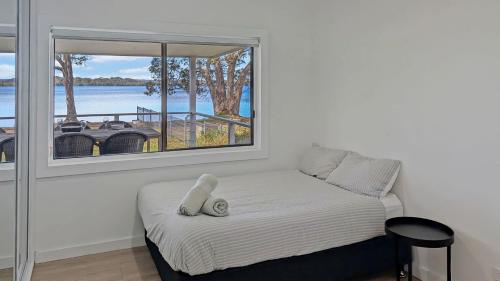 a bedroom with a bed with a large window at Billyz Basin by Experience Jervis Bay in St Georges Basin