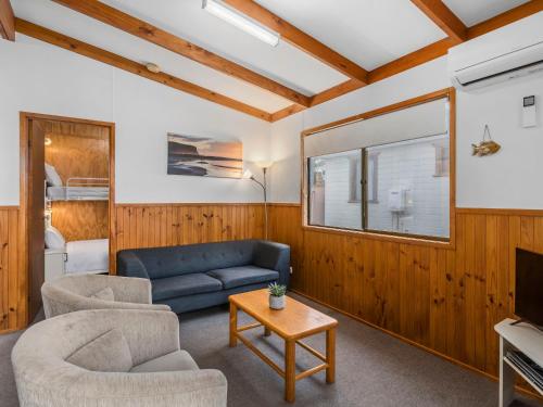 a living room with a couch and chairs and a tv at Joalah Holiday Park in Durras