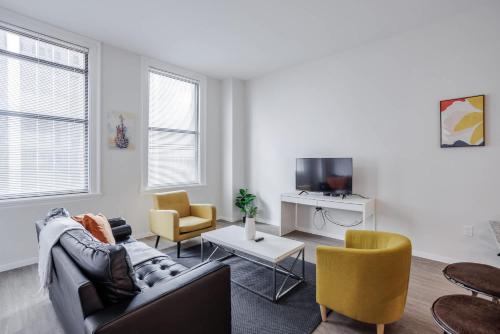 a living room with a couch and chairs and a tv at CozySuites Sky Central #7 in Cincinnati