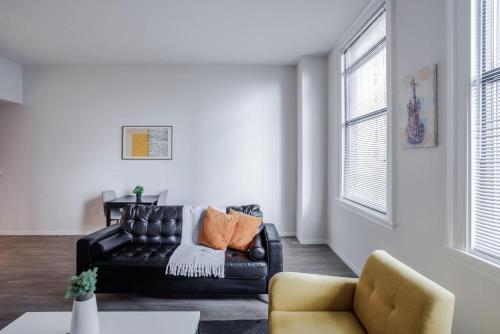 a living room with a black leather couch and a chair at CozySuites Sky Central #7 in Cincinnati