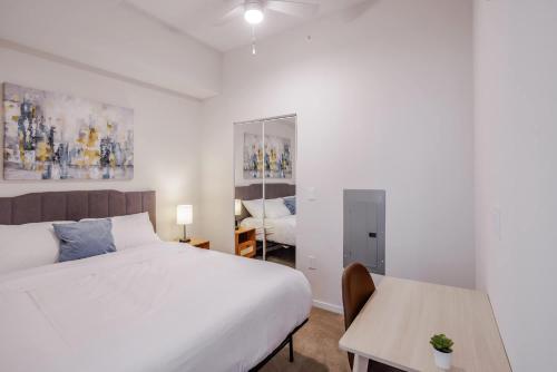 a white bedroom with a bed and a table at CozySuites Sky Central #9 in Cincinnati
