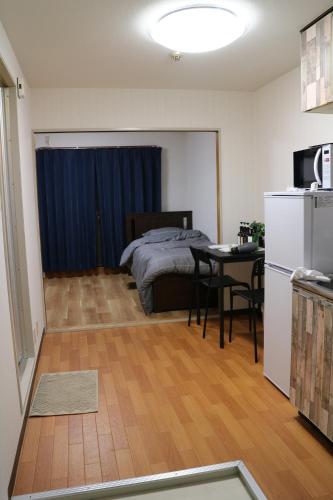a bedroom with a bed and a table and a kitchen at お宿あびこシルバーハイツ in Osaka
