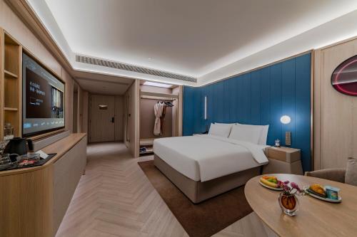 ein Hotelzimmer mit einem Bett und einem Fernseher in der Unterkunft Orange Crystal Hotel, Shenzhen Bao'An Joy City in Shenzhen