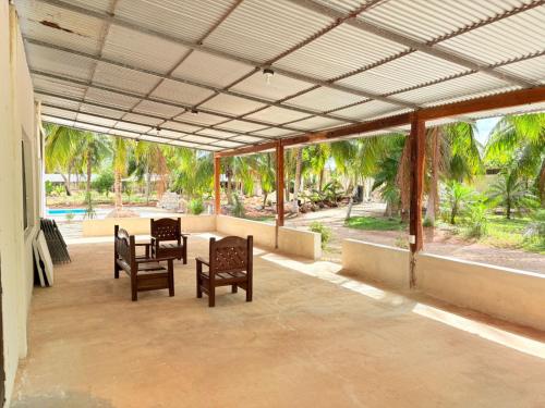 a patio with two chairs and a table and some trees at Casa limón Bacalar in Bacalar