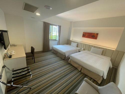a hotel room with two beds and a desk at C U Hotel Taichung in Taichung