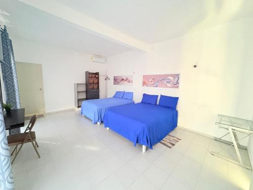 two beds in a white room with blue sheets at Casa limón Bacalar in Bacalar