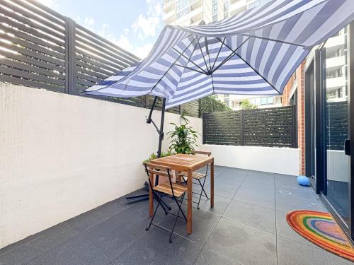 a patio with a table and a blue and white umbrella at Luxurious Apartment In heart of Bankstown CBD in Bankstown