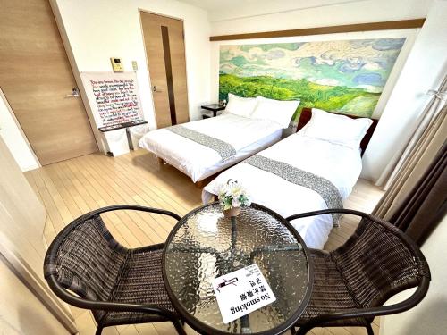 a small room with two beds and a table and chairs at 关西机场直达 i Home Osaka URBAN NOOK 舒适双床房 天下茶屋站步行3分钟 in Osaka