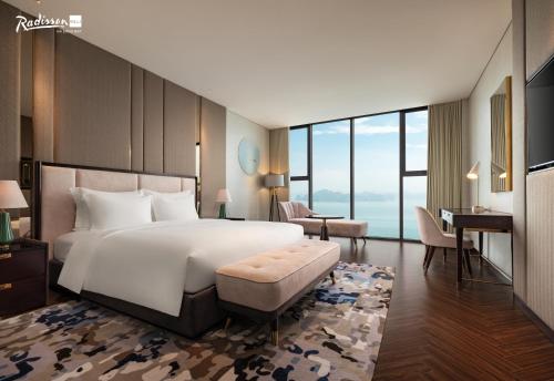 a bedroom with a large white bed and a desk at Radisson Blu Ha Long Bay in Ha Long