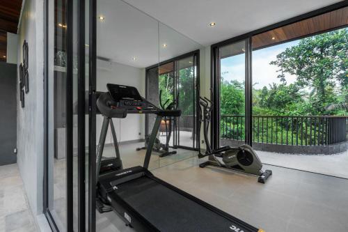a room with a gym with a treadmill and a large window at Villa Gayatri Sindu by BaliSuperHost in Ubud