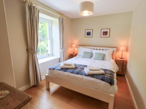 a bedroom with a bed with two lamps and a window at Mell View Cottage in Watermillock