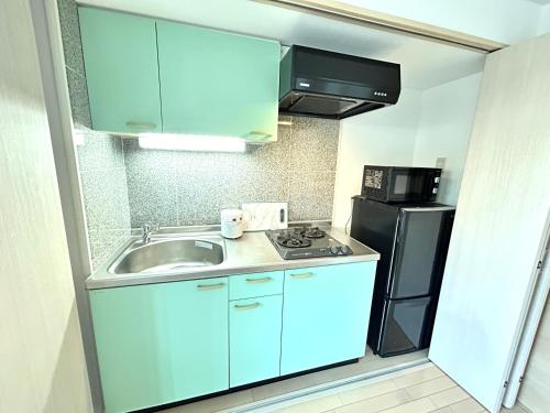 a small kitchen with a sink and a refrigerator at 关西机场直达 i Home Osaka URBAN NOOK 舒适双床房 天下茶屋站步行3分钟 in Osaka