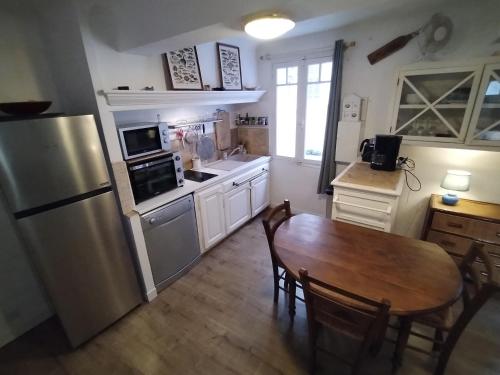 une cuisine avec une table et un réfrigérateur en acier inoxydable dans l'établissement Bel appartement Port Sanary, à Sanary-sur-Mer