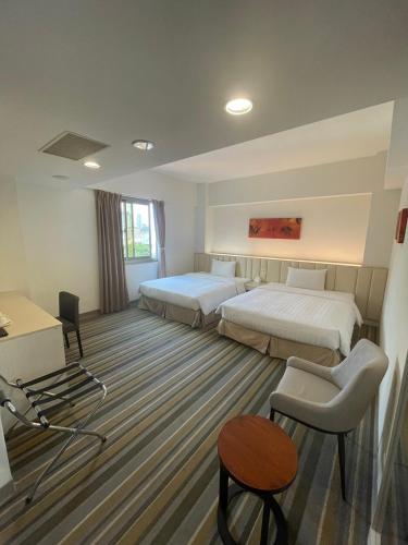 a hotel room with two beds and a desk at C U Hotel Taichung in Taichung
