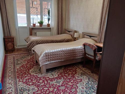 two beds in a room with a rug at Norik's Guest House in Sevan