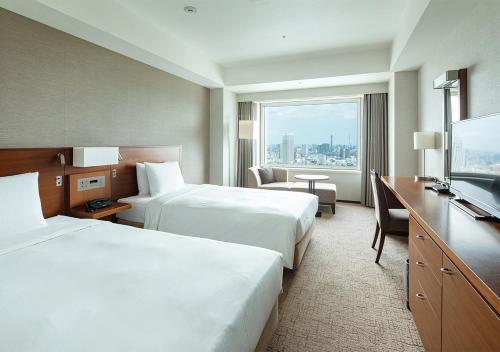 a hotel room with two beds and a flat screen tv at Odakyu Hotel Century Southern Tower in Tokyo