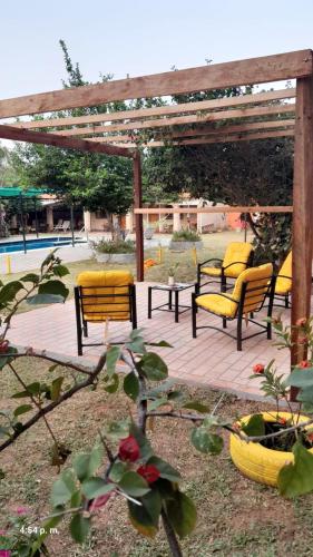 a patio with yellow chairs and a wooden pergola at Kitty Roga in Atyrá