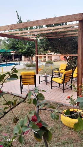 a patio with yellow chairs and a wooden pergola at Kitty Roga in Atyrá