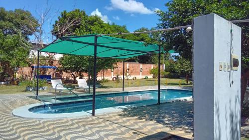 a swimming pool with a green umbrella over it at Kitty Roga in Atyrá