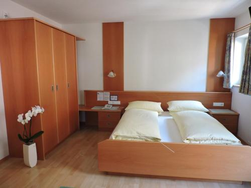 - une chambre avec un lit et une tête de lit en bois dans l'établissement Kühlerhof, à Anterselva di Mezzo