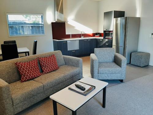 a living room with a couch and a chair and a table at 37 The Landing Motel in Whakatane