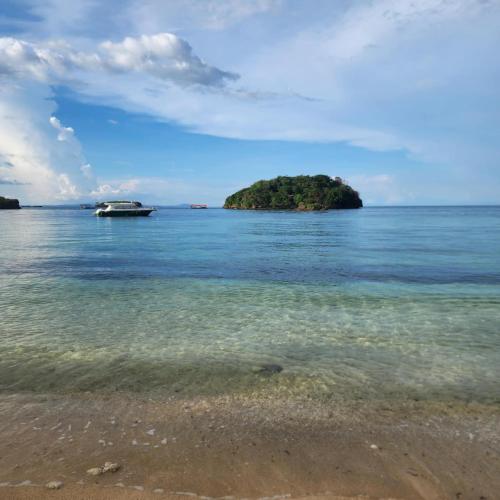 a small island in the ocean with a boat in the water at Mansueto's Beach Resort in Nabas