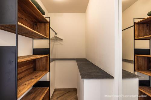 a walk in closet with wooden shelves at Op 't Roth 12 ruime sfeervolle vakantiewoning in 't groen in Oudenaarde