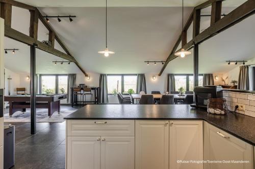 an open kitchen and living room with exposed beams at Op 't Roth 12 ruime sfeervolle vakantiewoning in 't groen in Oudenaarde