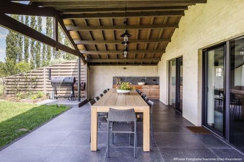 an outdoor patio with a wooden table and chairs at Op 't Roth 12 ruime sfeervolle vakantiewoning in 't groen in Oudenaarde