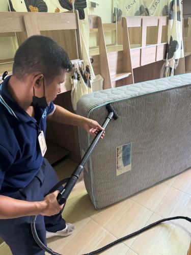 a man is cleaning a suitcase with a vacuum at Panda Lodge Home Stay in Bangkok