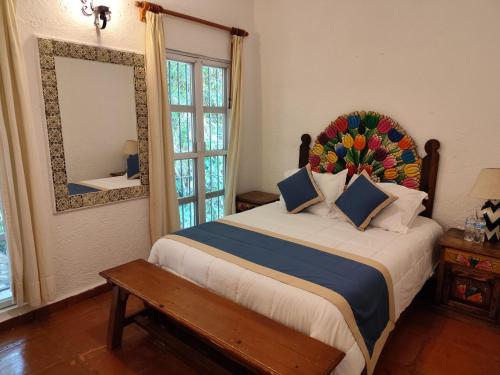 a bedroom with a large bed with a mirror and a bench at Casa de las Conchas Cuernavaca in Cuernavaca