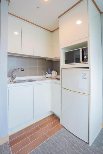 a white kitchen with a refrigerator and a microwave at Toyoko Inn Daejeon Government Complex in Daejeon