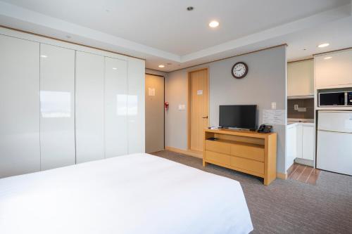 a bedroom with a bed and a tv and a kitchen at Toyoko Inn Daejeon Government Complex in Daejeon
