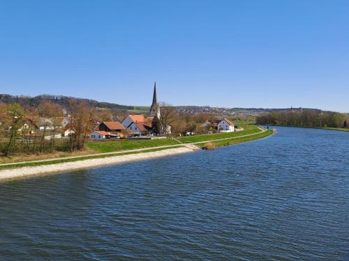 a view of a river with a church in the distance at Ferienwohnung am Donauradweg in Bad Abbach