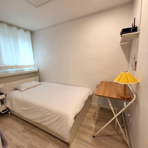 a small bedroom with a bed and a table at Humming stay in Seoul