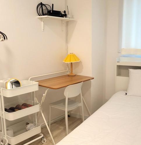 a small desk with a lamp on it next to a bed at Humming stay in Seoul