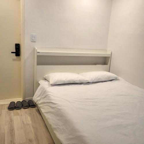 a bed with white sheets and two shoes on the floor at Humming stay in Seoul