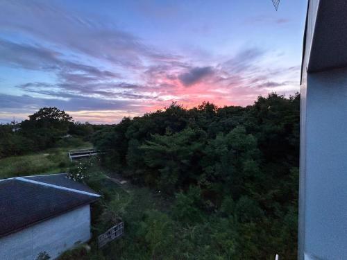 a sunset over a forest of trees with a building at グランピング宿 星空テラス&暖炉の庭付き戸建 Orion in Miyamae