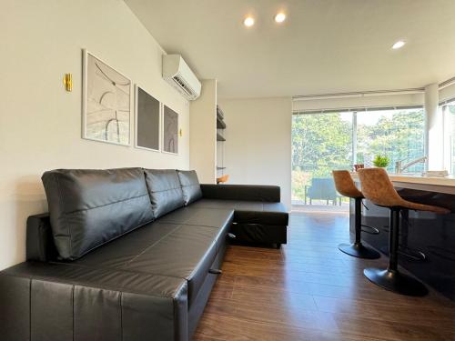 a black leather couch in a living room with a table at グランピング宿 星空テラス&暖炉の庭付き戸建 Orion in Miyamae