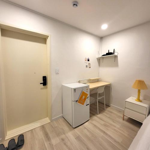 a room with a refrigerator and a desk with a lamp at Humming stay in Seoul