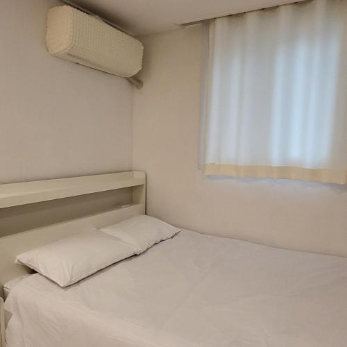 a small bedroom with a white bed and a window at Humming stay in Seoul