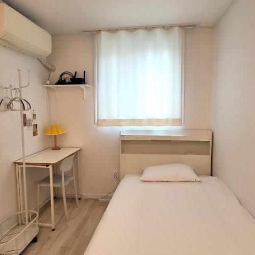 a small bedroom with a bed and a window at Humming stay in Seoul
