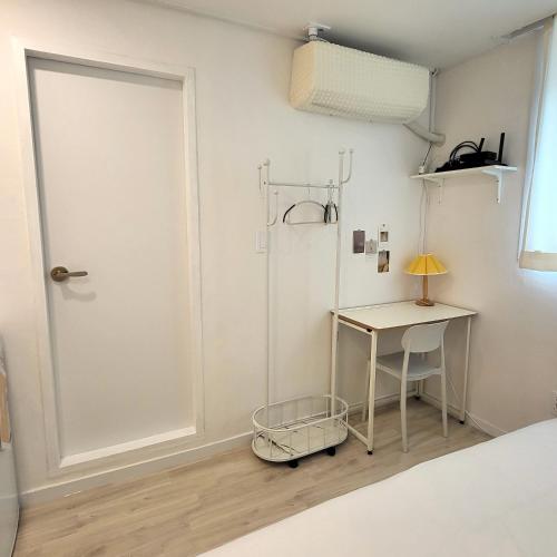 a bedroom with a door and a table and a desk at Humming stay in Seoul